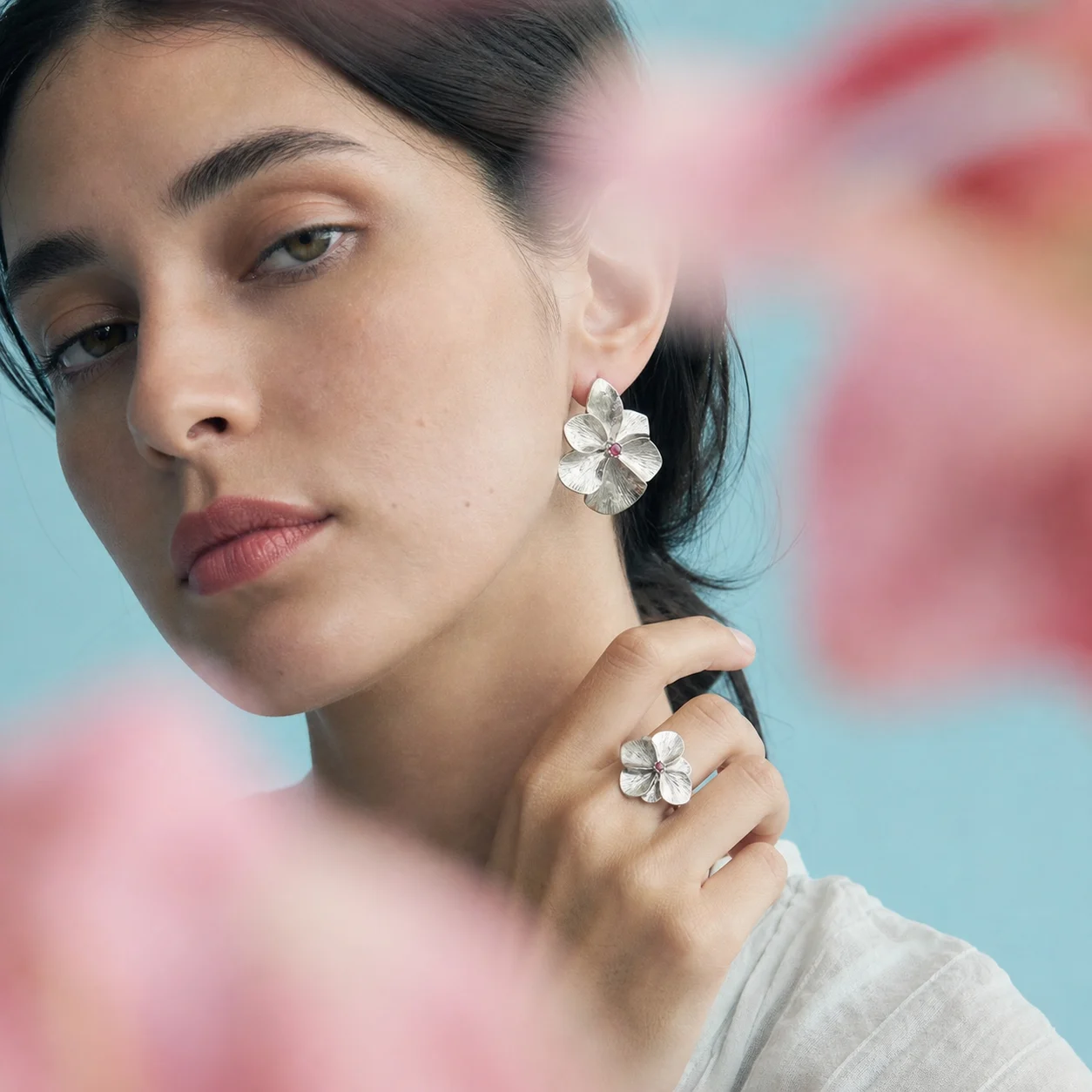 A woman wearing sculpted silver floral jewelry